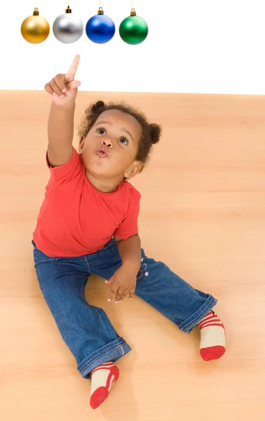 African baby girl pointing four balls of Christmas — Stock Photo, Image