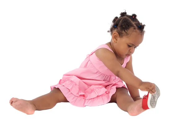 Beautiful african baby girl putting on an slipper — Stock Photo, Image
