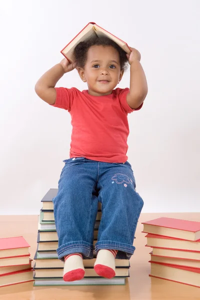 Dziecko siedzi na stos książek — Zdjęcie stockowe