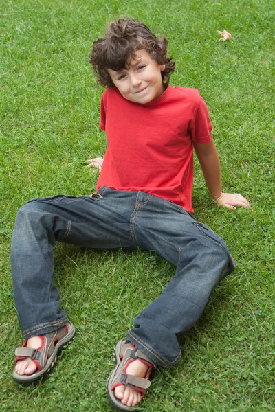 Ευτυχισμένο παιδί κάθεται στο γρασίδι — Φωτογραφία Αρχείου