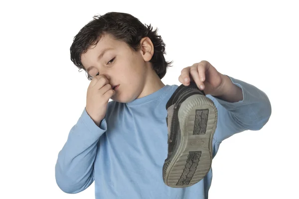 Ребенок с душистым носом берёт ботинок — стоковое фото