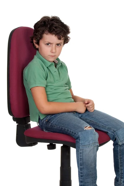 Злий маленький хлопчик сидить на великому стільці — стокове фото