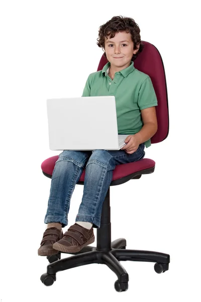 Симпатичный маленький мальчик сидит на большом стуле с ноутбуком — стоковое фото