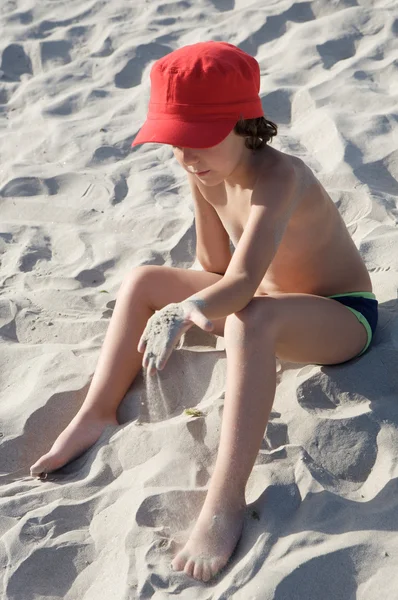 Ragazzo seduto sulla sabbia dalla spiaggia — Foto Stock