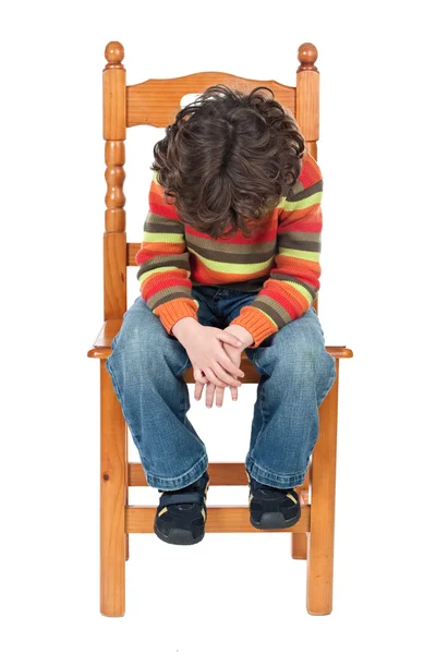 Trauriges Kind, das isoliert auf einem Stuhl sitzt — Stockfoto
