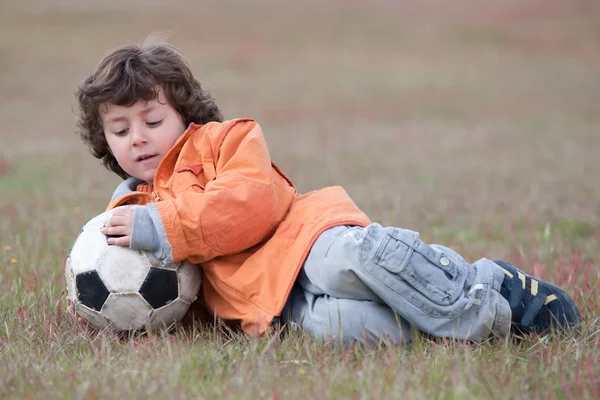Niño jugando con un balón de fútbol — Stok fotoğraf