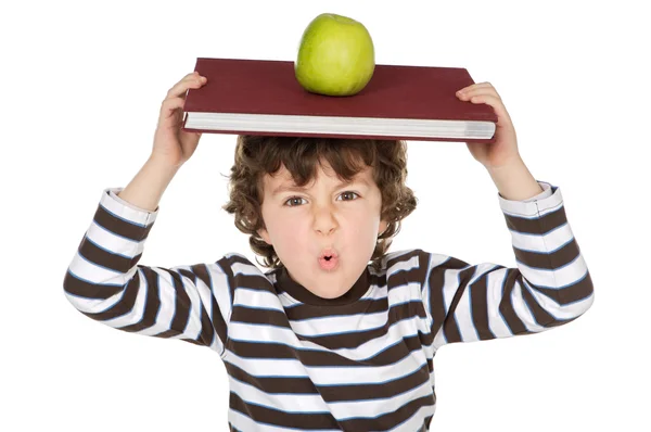Criança adorável estudando com livros e maçã na cabeça — Fotografia de Stock