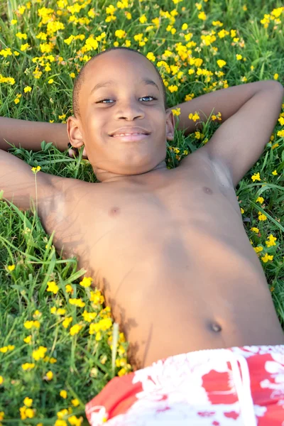 Ragazzo africano sdraiato sull'erba — Foto Stock