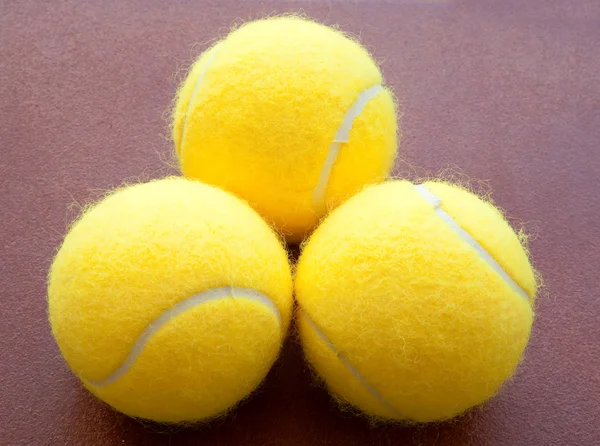 Tres pelotas de tenis juntas en amarillo sobre fondo marrón tres —  Fotos de Stock