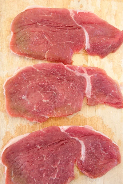 Tre bistecche di maiale crudo salato — Foto Stock