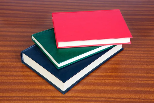 Três livros de capa dura em uma superfície de madeira — Fotografia de Stock