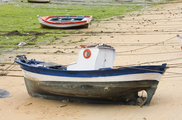 Csónak és kis halászfalu a hajó a homokban, alacsony árral — Stock Fotó