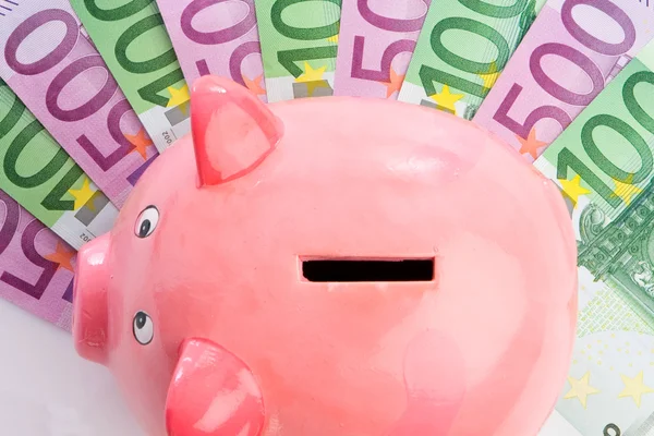 Pink piggy-bank over many notes — Stock Photo, Image