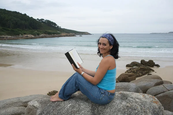 Mujer joven leyendo sentada en la playa — Foto de Stock