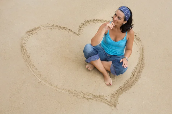 Hermosa chica sentada en el corazón en la playa —  Fotos de Stock