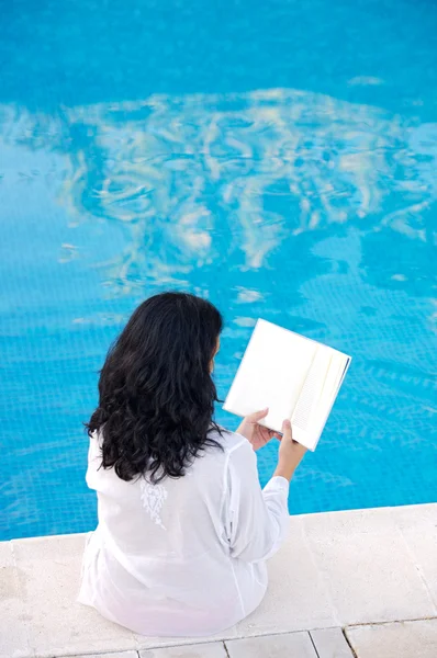 Senhora atraente lendo na piscina — Fotografia de Stock