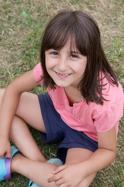 Piękna dziewczynka siedzi na trawie — Zdjęcie stockowe