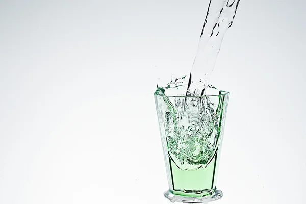 Stříkající vodě v zeleném nápojové sklo — Stock fotografie