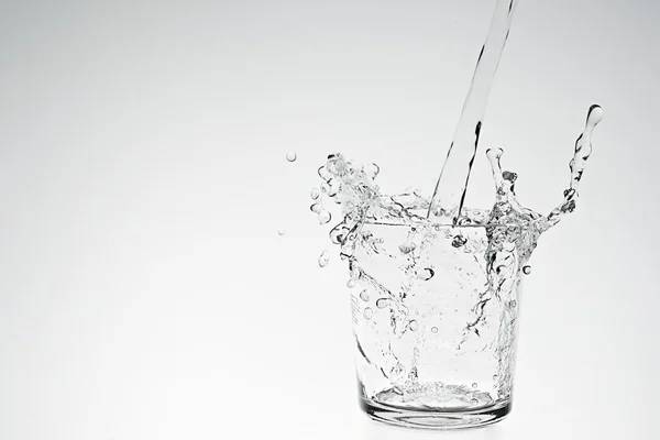 Stříkající vodě v nápojové sklo — Stock fotografie