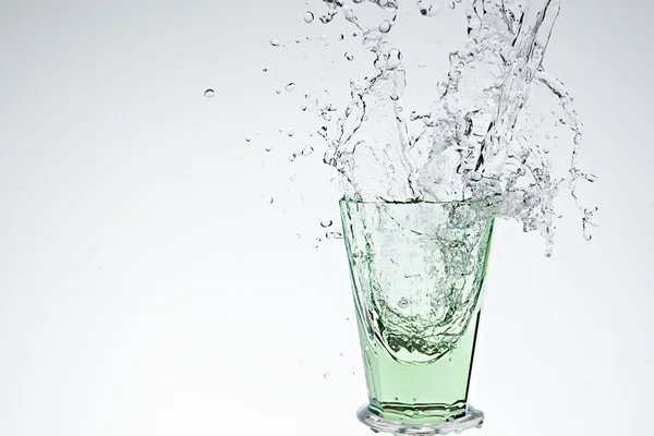 Stříkající vodě v zeleném nápojové sklo — Stock fotografie