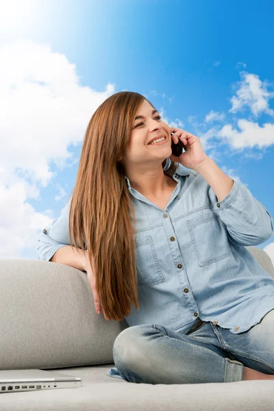 Brunette on couch talking on cellphone. — Stock Photo, Image