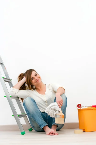 Młoda kobieta malarz siedzi na podłodze po malowaniu. — Zdjęcie stockowe
