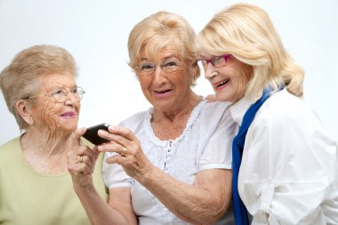 Elderly female friends with mobile device.