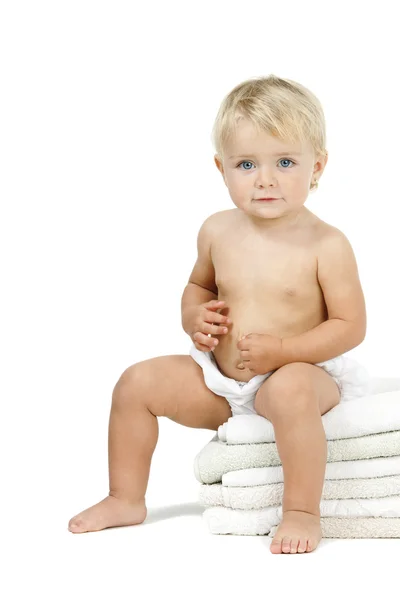 Baby girl sitting on pile towels — Stock Photo, Image