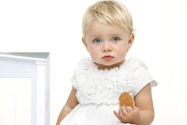 Скучный ребенок с печеньем в руке — стоковое фото