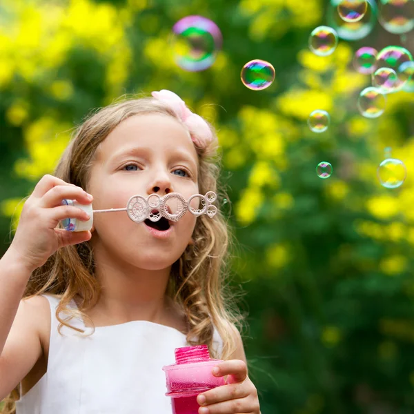 Cute girl blowing bubbles oudoors. — Stock Photo, Image