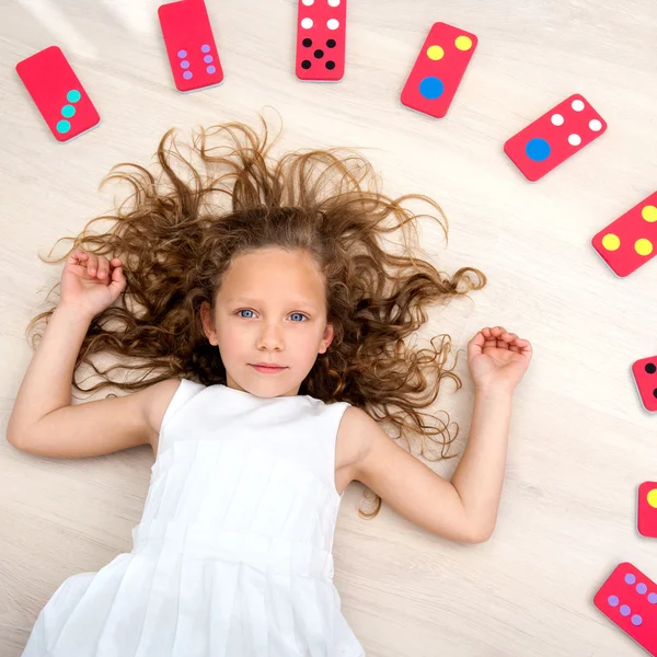 Jovem no chão com peças de dominó — Fotografia de Stock