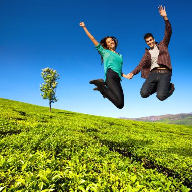 Jumping couple in green field. clipart