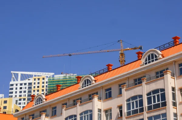 The roof of the house and construction crane — Stock Photo, Image