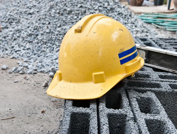 Chapéu duro de segurança amarelo colocando sobre tijolos — Fotografia de Stock