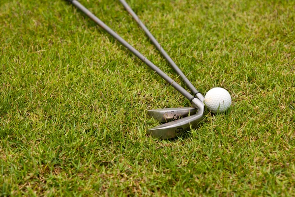 Bola de golfe e clube de golfe sentado na grama verde — Fotografia de Stock