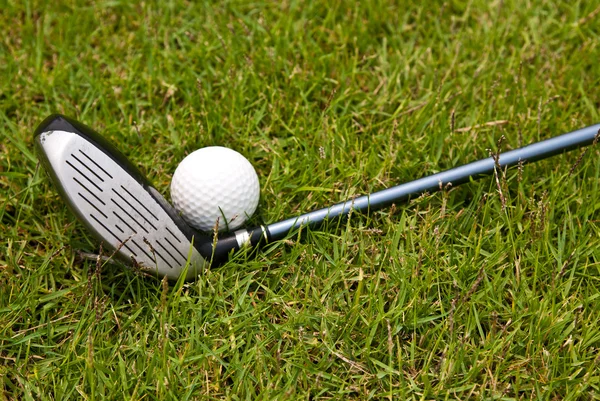 Bola de golfe e clube de golfe sentado na grama verde — Fotografia de Stock