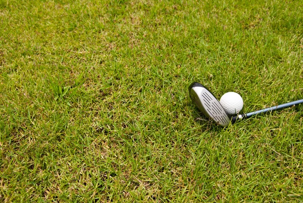 Golf ball and golf club sitting in green grass — Stock Photo, Image