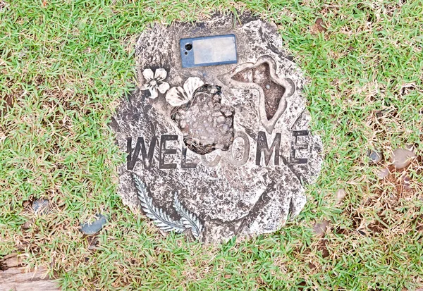 Разбитые приветственный камень на зеленом фоне травы — стоковое фото