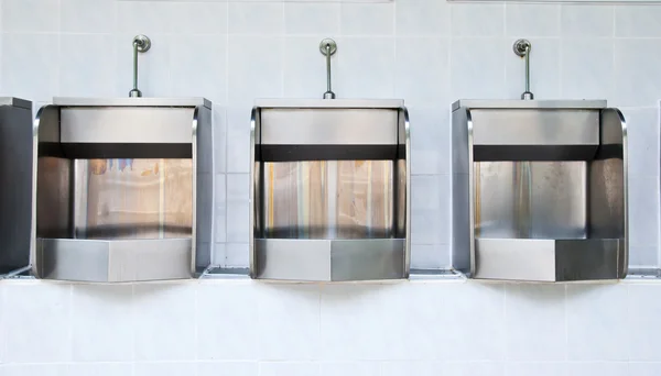 En række urinaler i flisebelagt væg i et offentligt toilet - Stock-foto