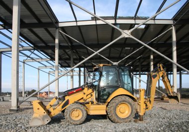 Wheeled tractor on modern storehouse construction site clipart