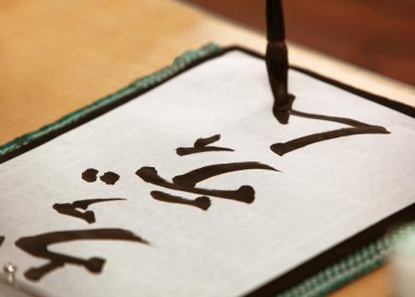 Close up of male hand writing Japanese characters clipart