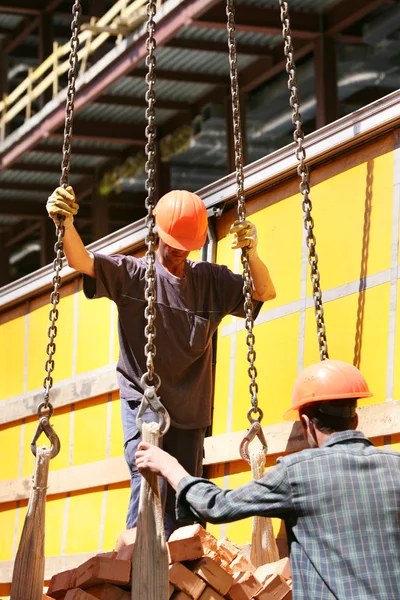 Werknemers en bakstenen op de bouwplaats — Stockfoto
