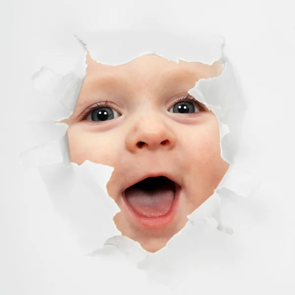 Baby looking through paper hole — Stock Photo, Image
