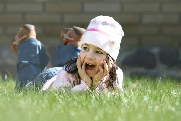 Klein meisje opleggen van groen gras — Stockfoto