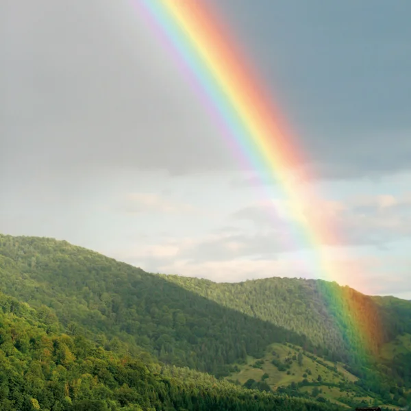 Arco-íris brilhante sobre colinas verdes — Fotografia de Stock