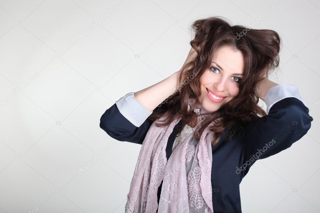 Brunette girl touching hair over gray background. Studio shot wi