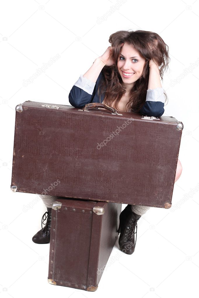 Young attractive girl is sitting on a vintage cases. Studio shot