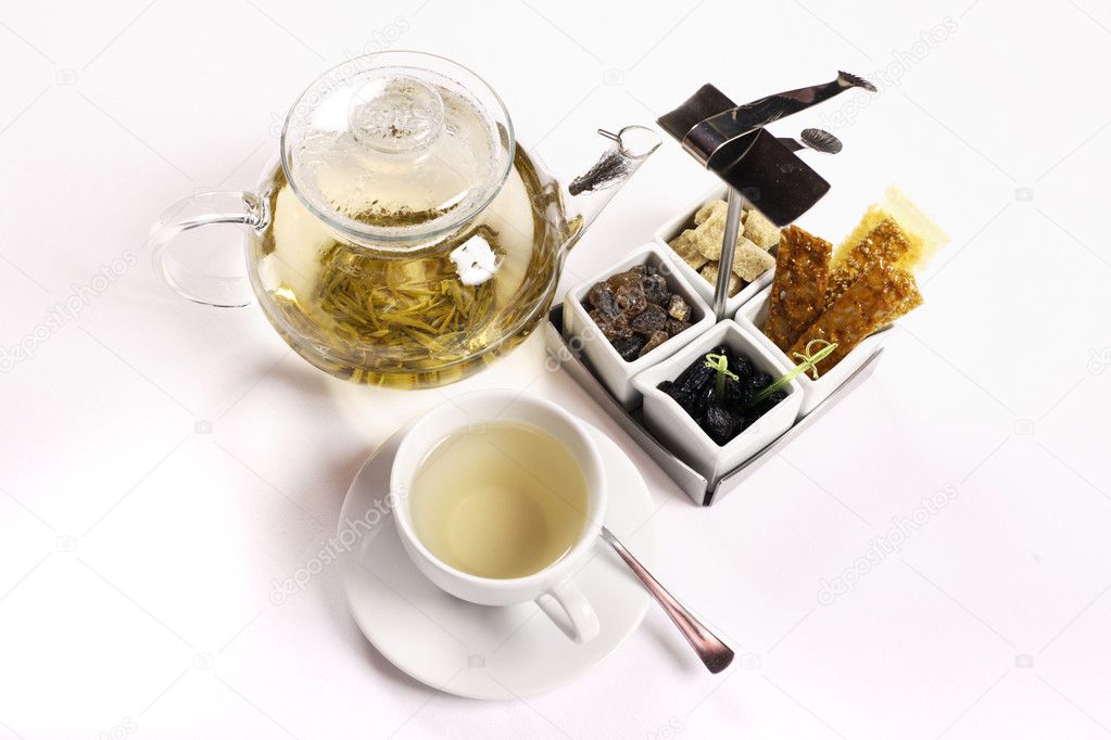 Transparent teapot with green tea, cup, saucer, sugar and other