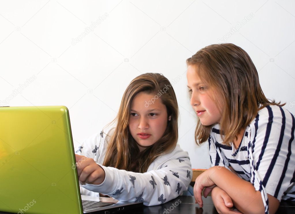 Teen sisters studying on laptop