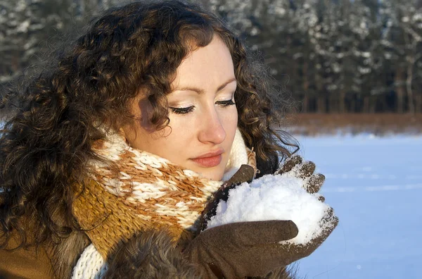 Schöne lockige Mädchen hält den Schnee — Stockfoto